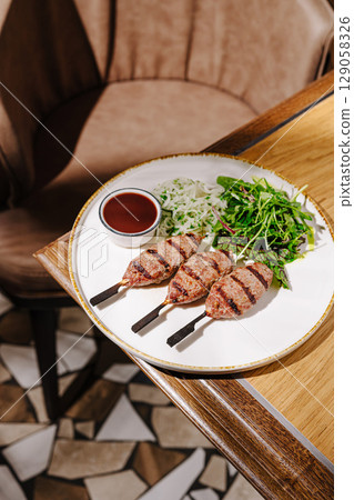 Grilled meat skewers served with fresh salad on wooden table Grilled meat skewers served with fresh salad on wooden table 129058326