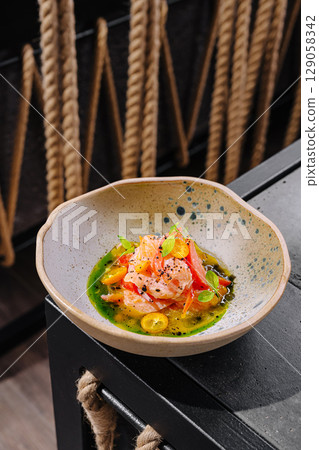 Delicious plate of vibrant seafood dish served in unique bowl 129058342