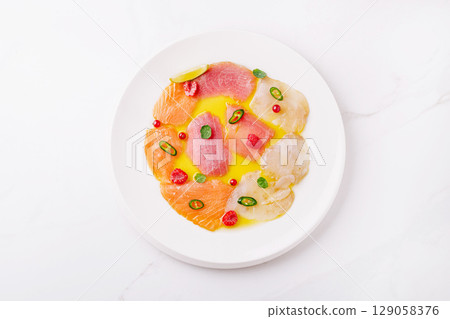Citrus-infused sashimi platter served on a white plate with garnishes Citrus-infused sashimi platter served on a white plate with garnishes 129058376