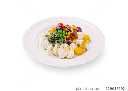 Colorful assortment of mozzarella with fresh cherry tomatoes on a white plate 129058392