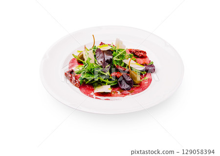 Fresh salad with beef carpaccio and mixed greens served on a white plate 129058394