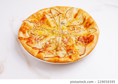 Creative pear and cheese pizza topped with nuts and honey drizzle 129058395
