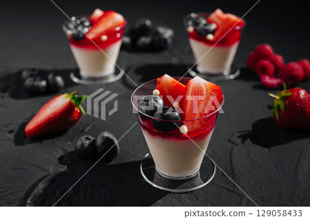 Delicious berry panna cotta desserts served on a dark background Delicious berry panna cotta desserts served on a dark background 129058433