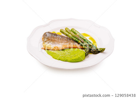 Grilled fish with asparagus and green puree served on white plate Grilled fish with asparagus and green puree served on white plate 129058438