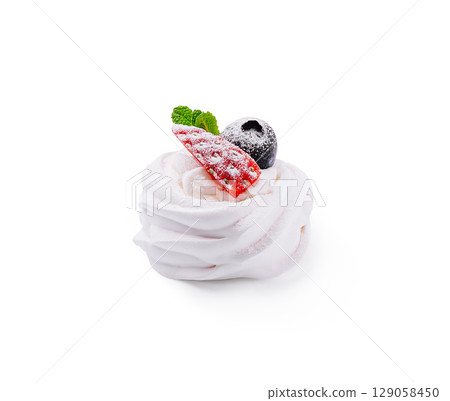 Delicious meringue dessert topped with berries and mint at a kitchen table 129058450