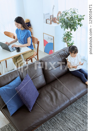 Mother working from home and child enjoying tablet Mother working from home and child enjoying tablet 129058471