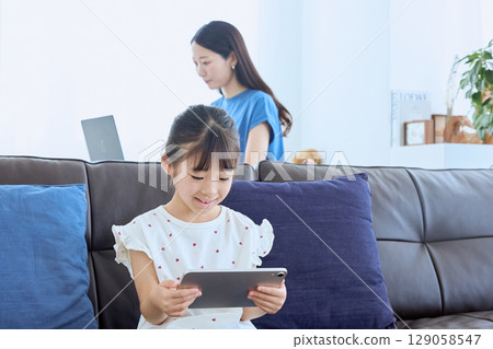 Mother working from home and child enjoying tablet Mother working from home and child enjoying tablet 129058547