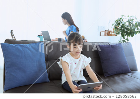 Mother working from home and child enjoying tablet 129058562