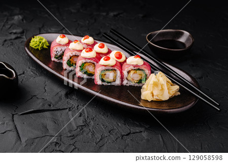 Delicious sushi rolls served on a dark plate with wasabi and ginger Delicious sushi rolls served on a dark plate with wasabi and ginger 129058598