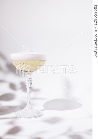 Elegant cocktail served in a clear glass with a frothy top in soft light Elegant cocktail served in a clear glass with a frothy top in soft light 129058602