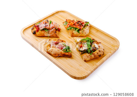 Delicious variety of flatbreads topped with fresh ingredients on wooden tray Delicious variety of flatbreads topped with fresh ingredients on wooden tray 129058608
