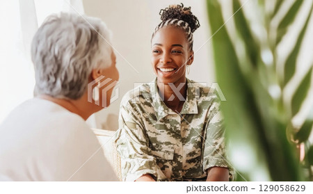 Armed Forces Day female soldier smiling and talking with elderly woman indoors Armed Forces Day female soldier smiling and talking with elderly woman indoors 129058629