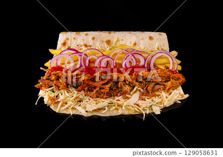 Tasty pulled meat sandwich with fresh toppings on a black background Tasty pulled meat sandwich with fresh toppings on a black background 129058631