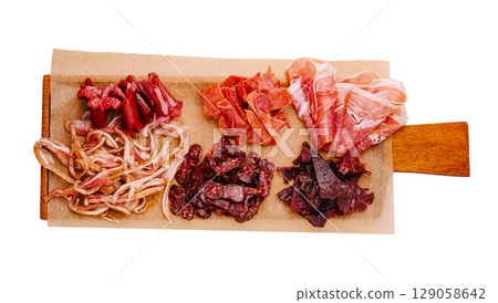 Variety of dried meats on a wooden board prepared for tasting 129058642