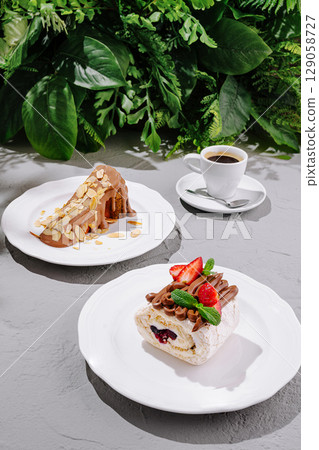 Delicious desserts served on plates with coffee in a lush green setting Delicious desserts served on plates with coffee in a lush green setting 129058727