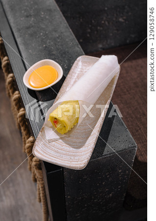 Delicious spring roll served with sauce in a modern dining setting 129058746