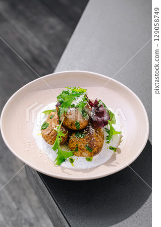 Deliciously crafted savory potatoes garnished with greens on a sleek table Deliciously crafted savory potatoes garnished with greens on a sleek table 129058749