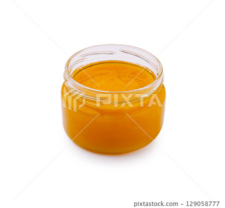 Bright golden honey jar in a clear glass container on a white background Bright golden honey jar in a clear glass container on a white background 129058777