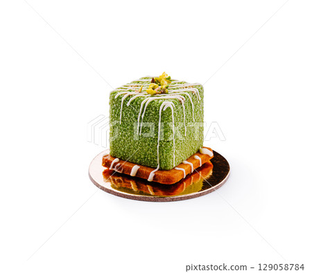 Square green dessert topped with nuts and drizzled icing on golden plate Square green dessert topped with nuts and drizzled icing on golden plate 129058784
