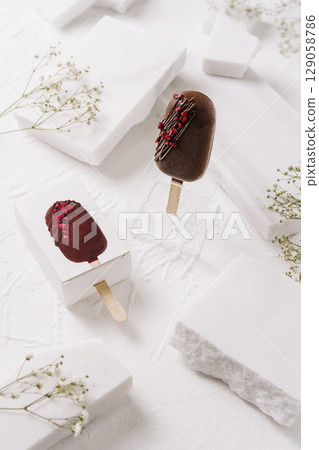 Delicious chocolate ice cream popsicles on a minimalist white background Delicious chocolate ice cream popsicles on a minimalist white background 129058786