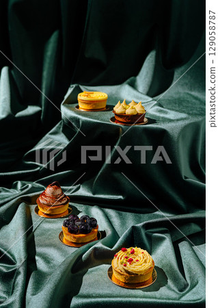 Elegant dessert display featuring various pastries on green fabric 129058787
