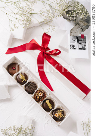 Graduation gift box featuring chocolates, flowers, and a cap symbolizing success 129058790