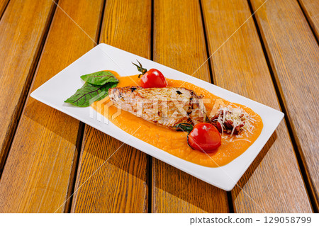 Grilled fish fillet served on squash puree with cherry tomatoes Grilled fish fillet served on squash puree with cherry tomatoes 129058799
