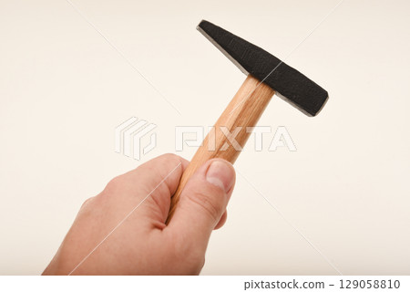 A small hammer with a wooden handle. A hammer on a white background in his hand. 129058810