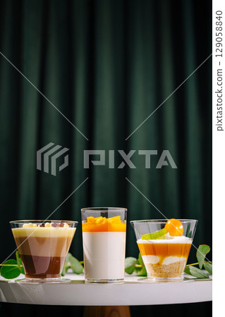 Three colorful dessert cups arranged on a table in a cozy setting 129058840