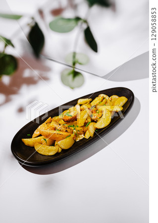 Golden roasted potatoes with herbs on a serving plate Golden roasted potatoes with herbs on a serving plate 129058853
