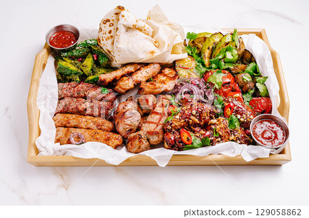 Delicious meat platter featuring various grilled dishes served with sauces 129058862