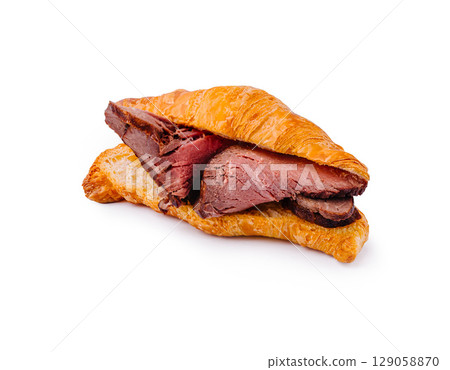Delicious croissant sandwich filled with tender roast beef Delicious croissant sandwich filled with tender roast beef 129058870