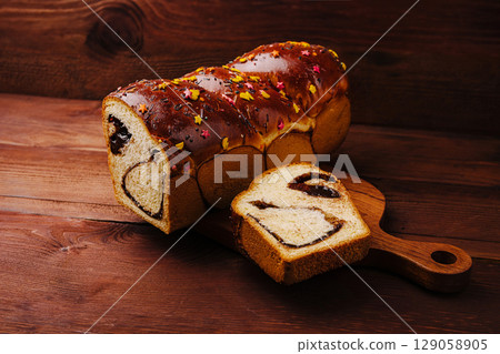 Sweet bread with chocolate filling and sprinkles on wood 129058905