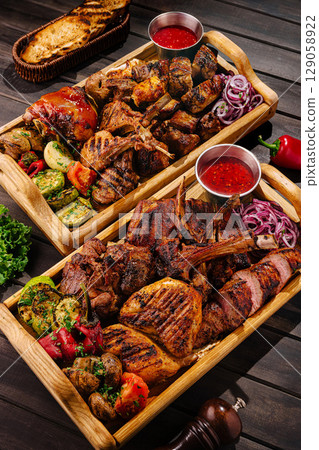 Delicious assortment of grilled meats served on wooden platter 129058922