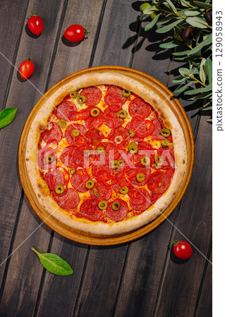 Delicious pepperoni pizza topped with green olives and fresh ingredients 129058943