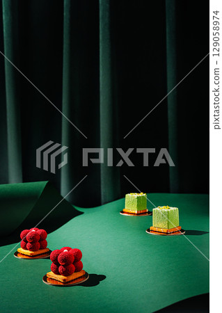 Exquisite dessert display with colorful cakes on green backdrop Exquisite dessert display with colorful cakes on green backdrop 129058974