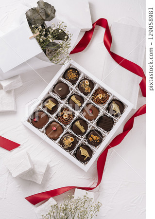 Elegant box of assorted chocolates with delicate decorations and ribbon 129058981