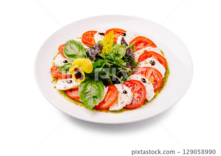 Fresh caprese salad with basil, tomatoes, and mozzarella on a white plate 129058990