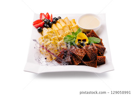 Delicious dessert platter featuring fruits and sweet treats on a white plate Delicious dessert platter featuring fruits and sweet treats on a white plate 129058991