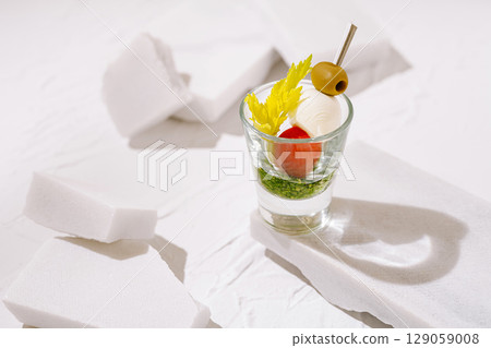 Creative cocktail served in glass with garnish on minimalist background 129059008