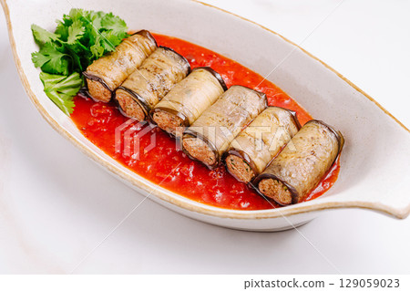 Delicious eggplant rolls with savory meat filling served in rich tomato sauce 129059023