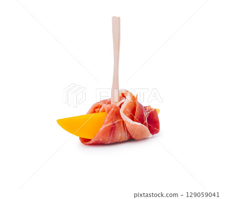 Unique appetizer featuring cured meat and cheese presented on a stick 129059041