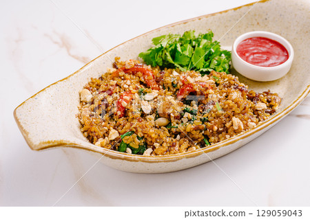 Flavorful quinoa salad garnished with herbs and sauce served in a bowl Flavorful quinoa salad garnished with herbs and sauce served in a bowl 129059043