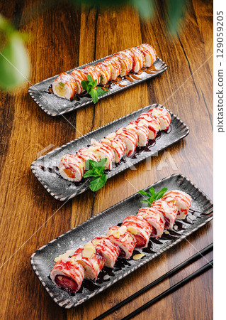 Delicious sushi rolls beautifully displayed on elegant black plates Delicious sushi rolls beautifully displayed on elegant black plates 129059205