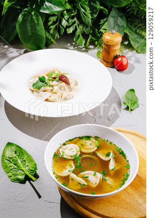 Fresh dumplings in broth with vibrant greens and herbs on display 129059217
