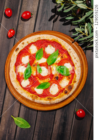Freshly baked pizza with tomato and mozzarella on wooden platter Freshly baked pizza with tomato and mozzarella on wooden platter 129059226