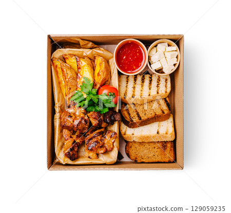 Delicious grilled chicken with bread and tomato served in a takeout box 129059235