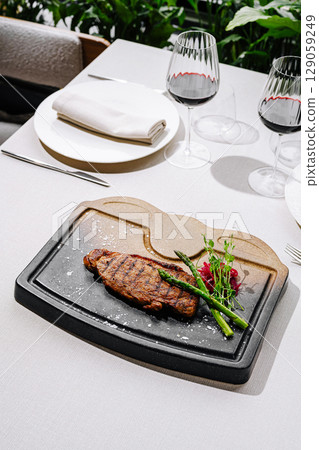 Grilled steak served on a sizzling stone platter in outdoor dining setting 129059249
