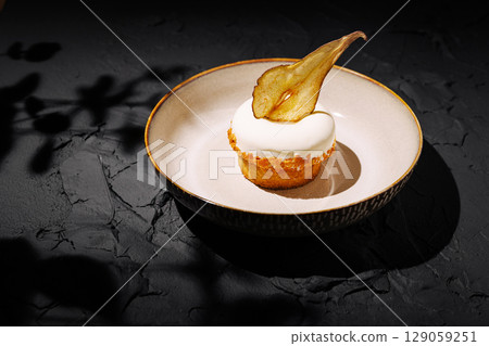 Delicious dessert featuring cream topping with dried fruit on dark surface Delicious dessert featuring cream topping with dried fruit on dark surface 129059251