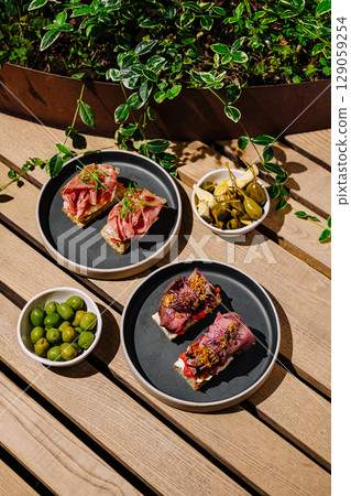 Delicious tapas served on plates with olives in a vibrant outdoor setting 129059254